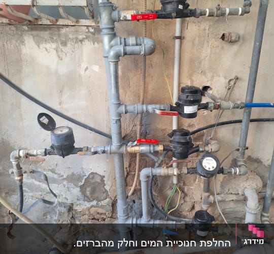 צנרת מים עם ברזים ומדי מים על קיר חיצוני